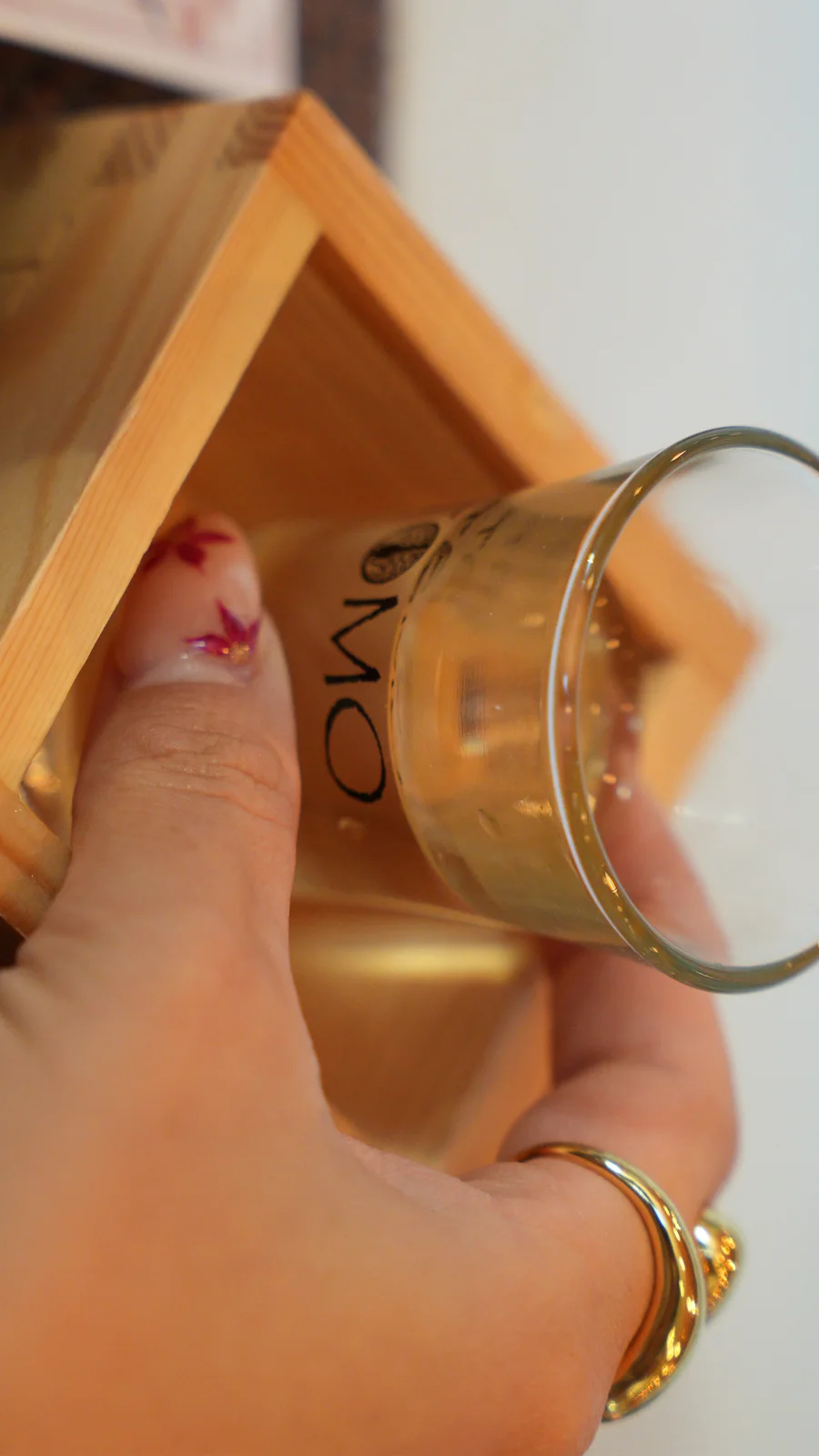 A glass of sake held over a Tomo masu box at the barrel ceremony