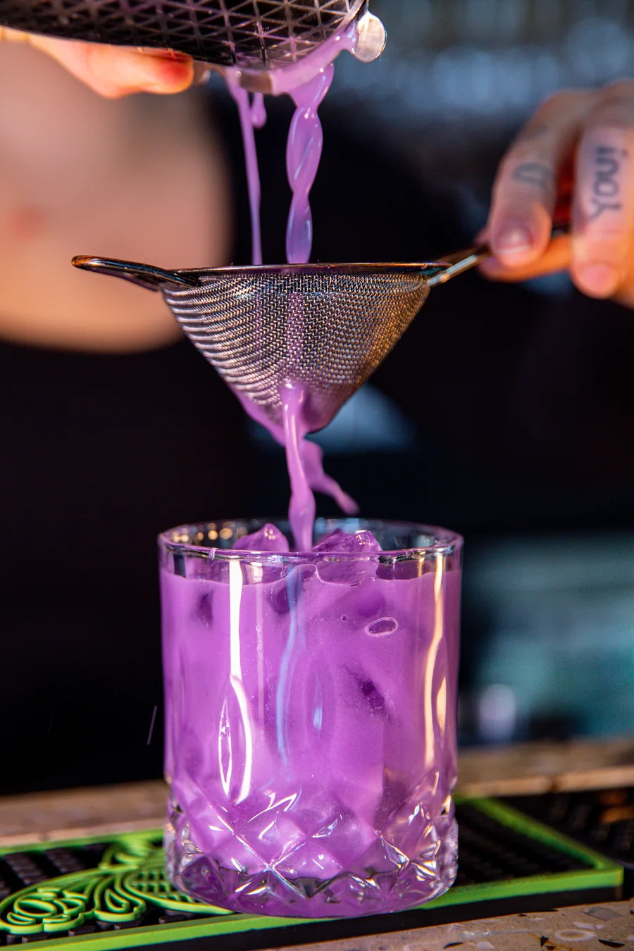 A cocktail double-strained into the glass at the Tomo Japanese bar