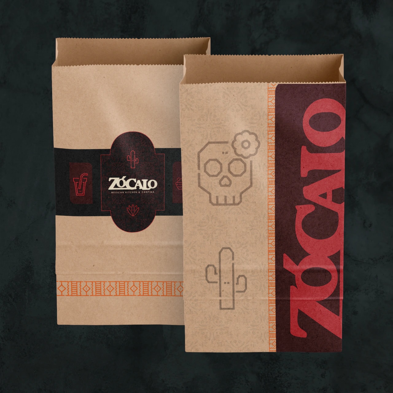 Two kraft paper takeout bags branded for Zócalo, one with a burgundy label band and one with a skull, a cactus and the wordmark in red